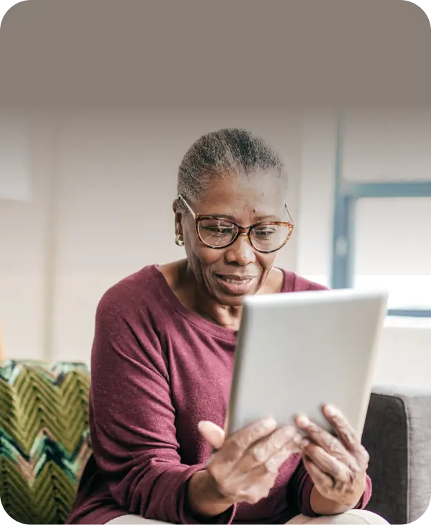 An elderly woman focused on using an iPad, sitting comfortably